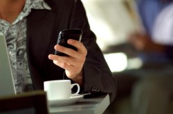Young urban businessman using Blackberry PDA in cafe.
